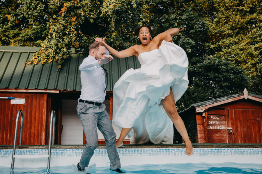 Bride and groom jumping into a swimming pool during their wedding, captured through candid wedding photography.